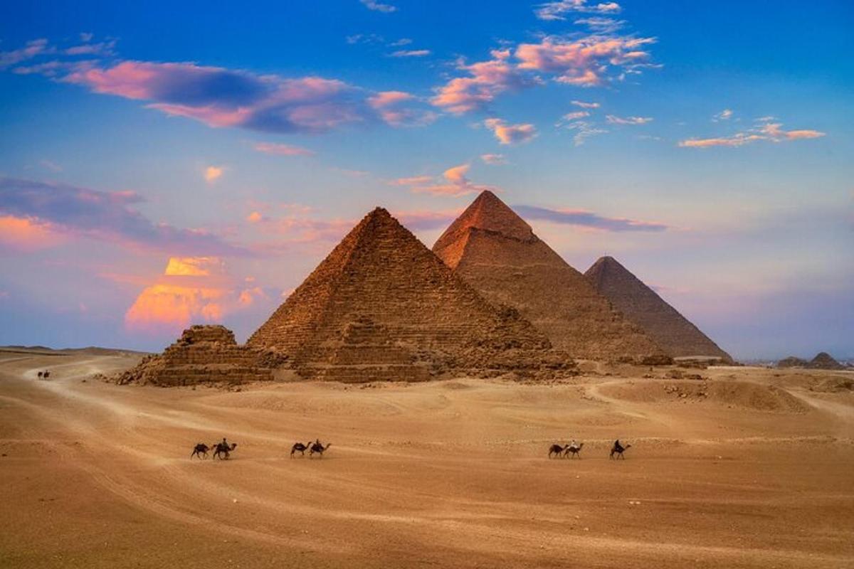 Skupina lidí na koních před pyramidami