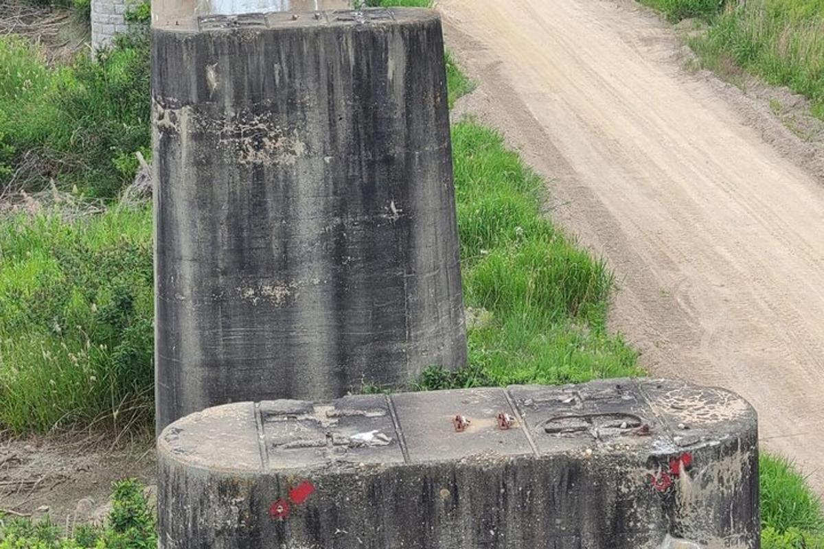 un stâlp de lemn pe marginea unui drum de pământ
