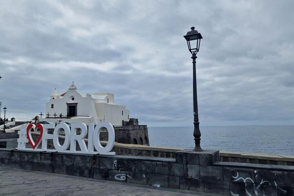 un cartello su un muro con un lampione e l'oceano