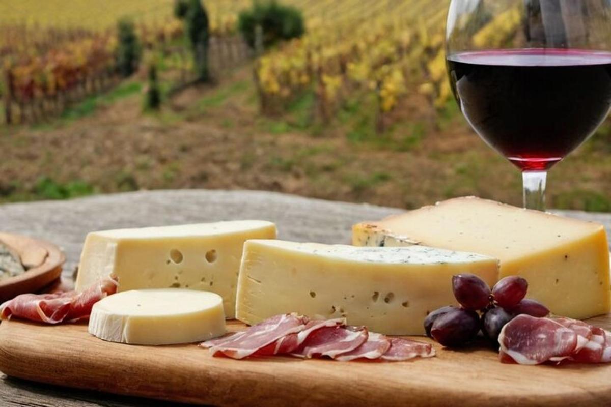 une planche à découper en bois avec du fromage et un verre de vin