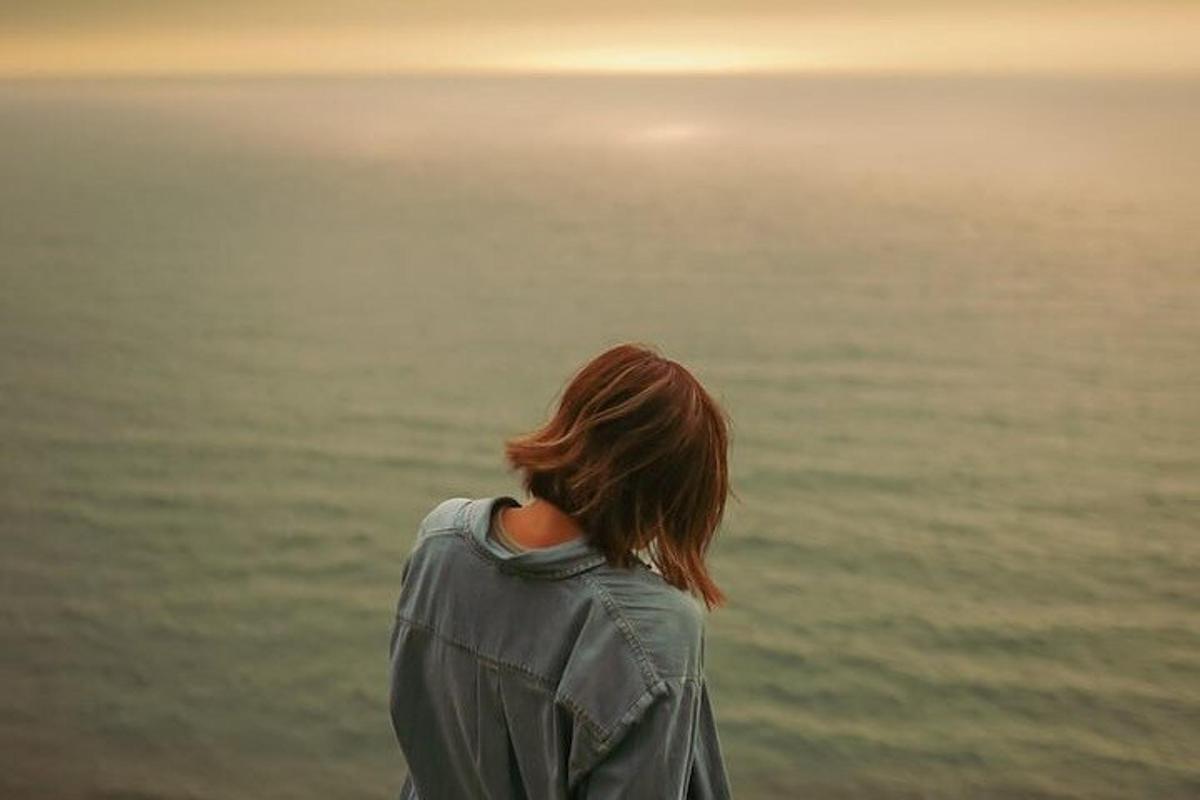 una donna che guarda l'oceano al tramonto