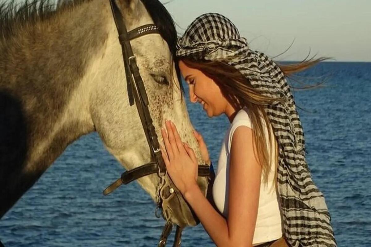een vrouw staat naast een paard