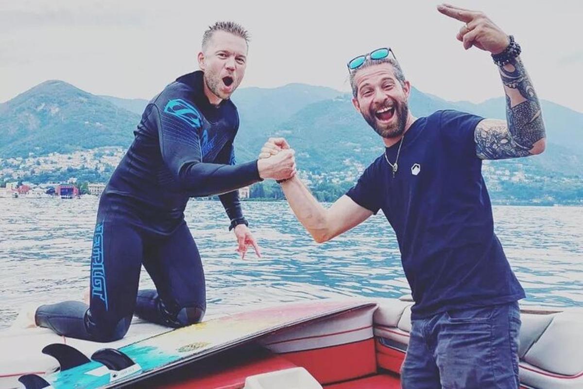 Dos hombres están de pie sobre una tabla de surf en el agua.