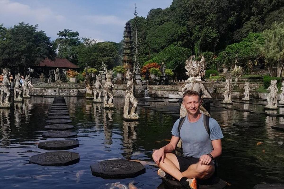 seorang lelaki duduk di dalam air di hadapan sebuah kuil