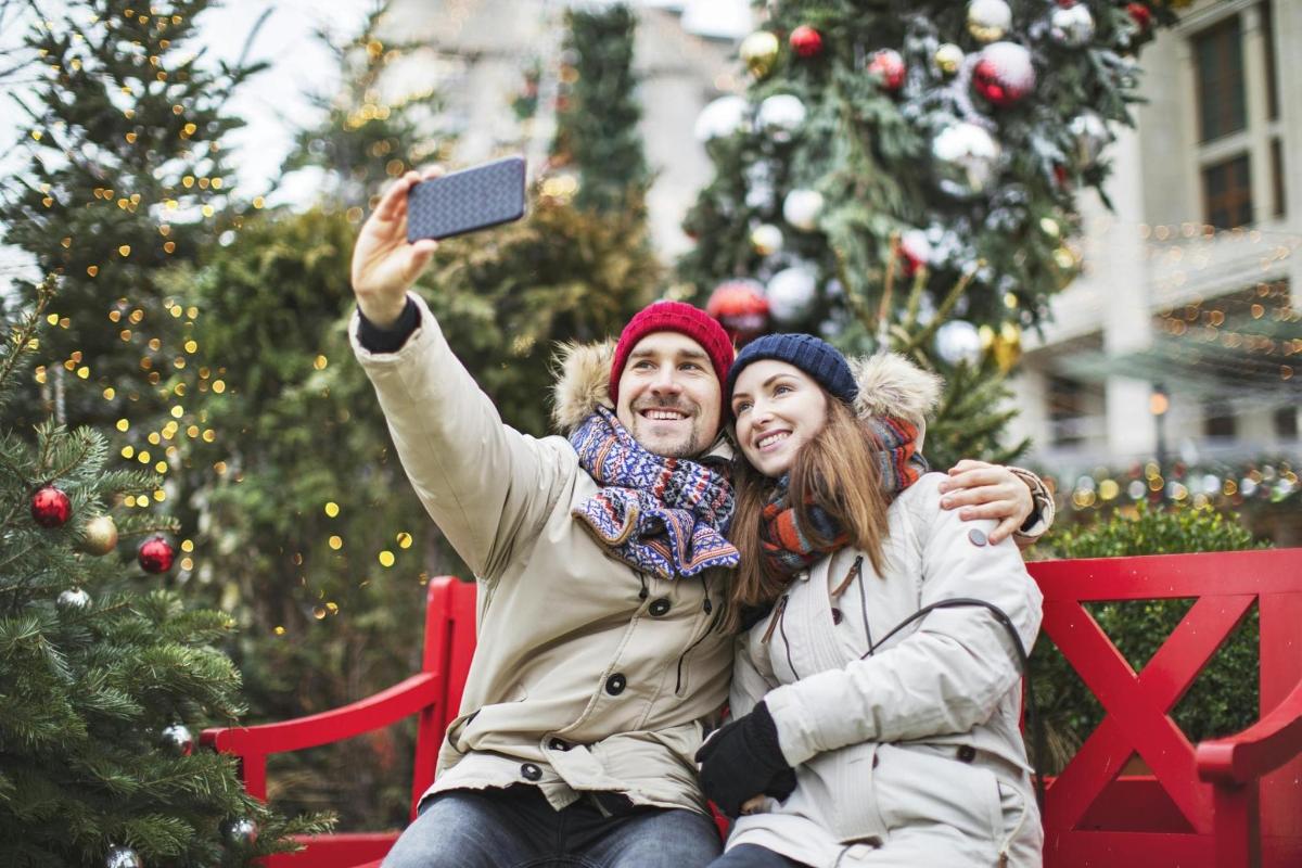 Dos personas sentadas en un banco tomándose una foto con un teléfono celular