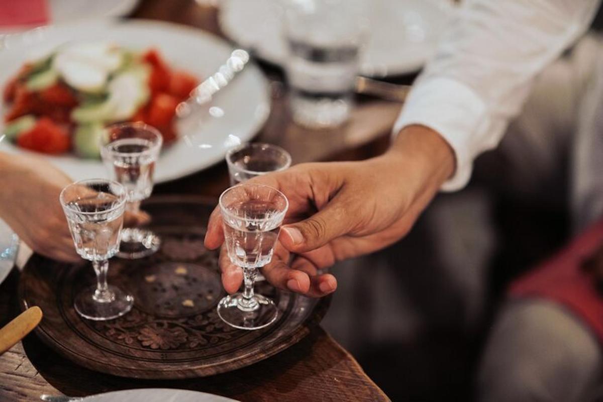 vīrietis tur vīna glāzi uz galda