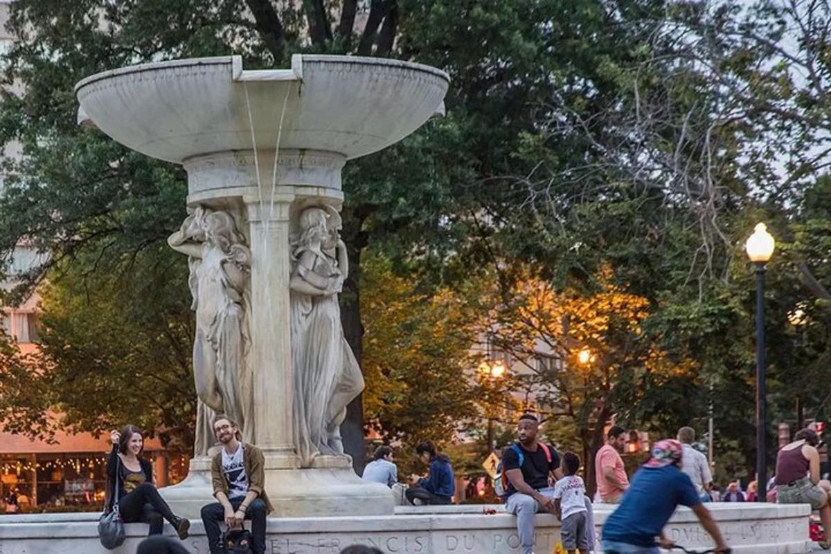 un grup de persones assegudes al voltant d'una font en un parc