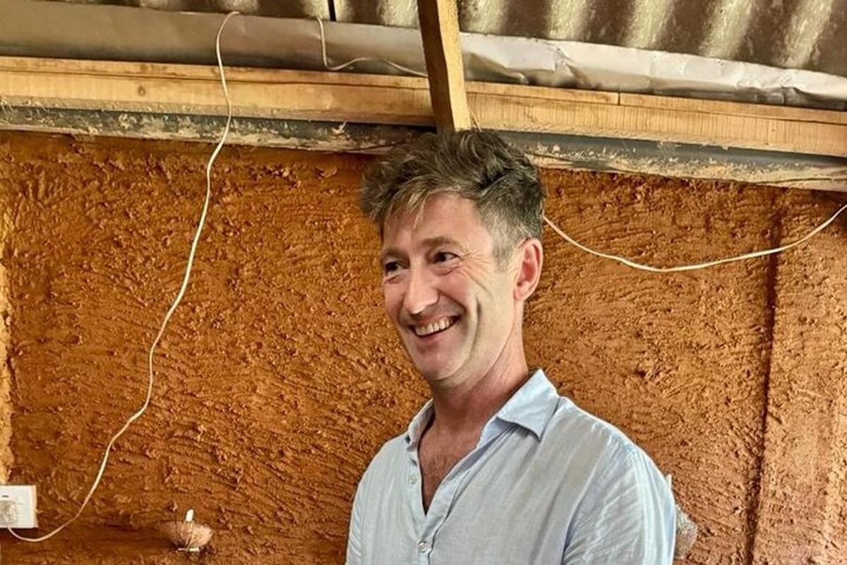 a man standing in front of a brown wall
