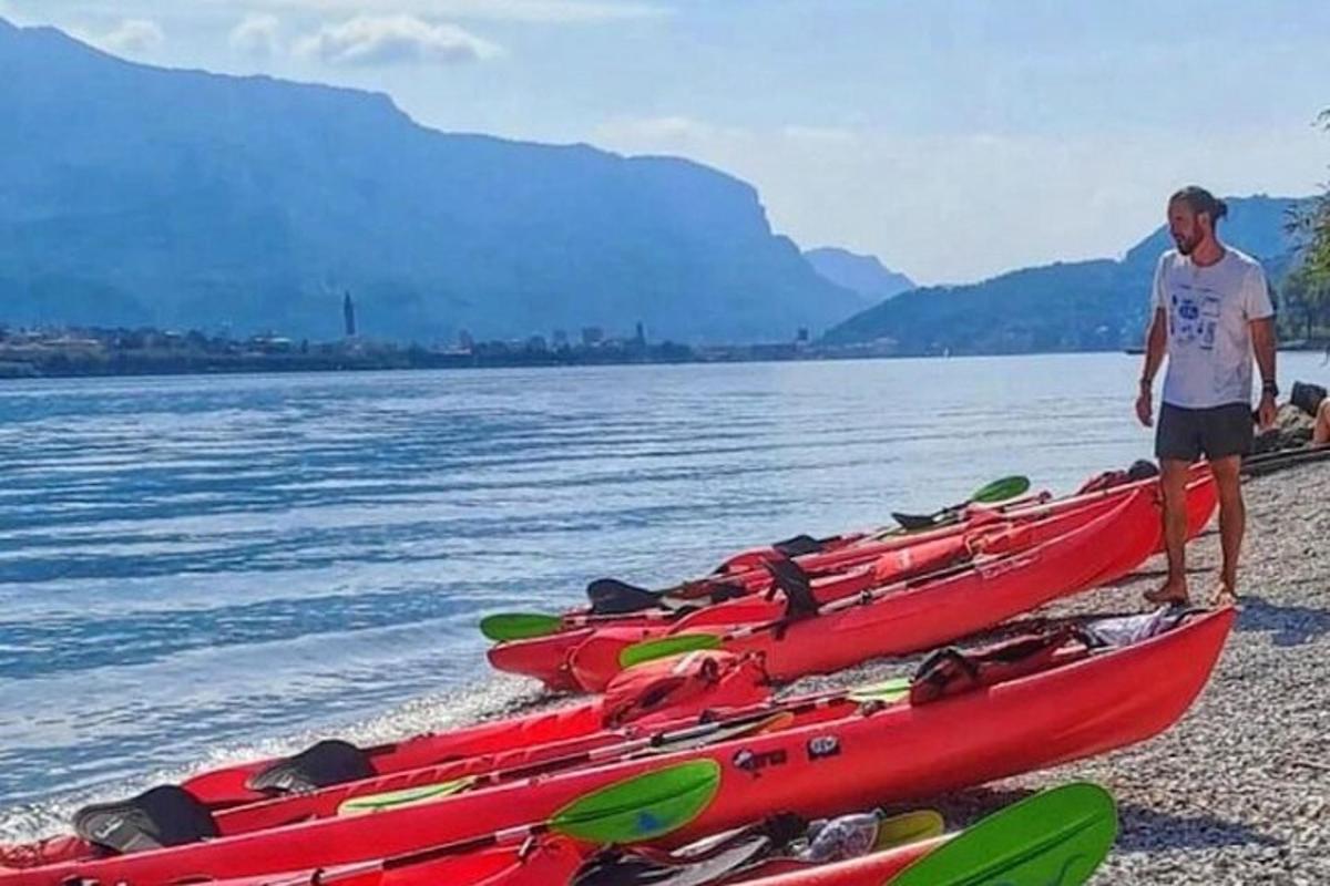 seorang pria berdiri di samping deretan kayak di pantai