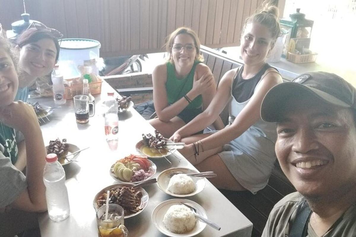 sekelompok orang yang duduk mengelilingi meja dengan makanan