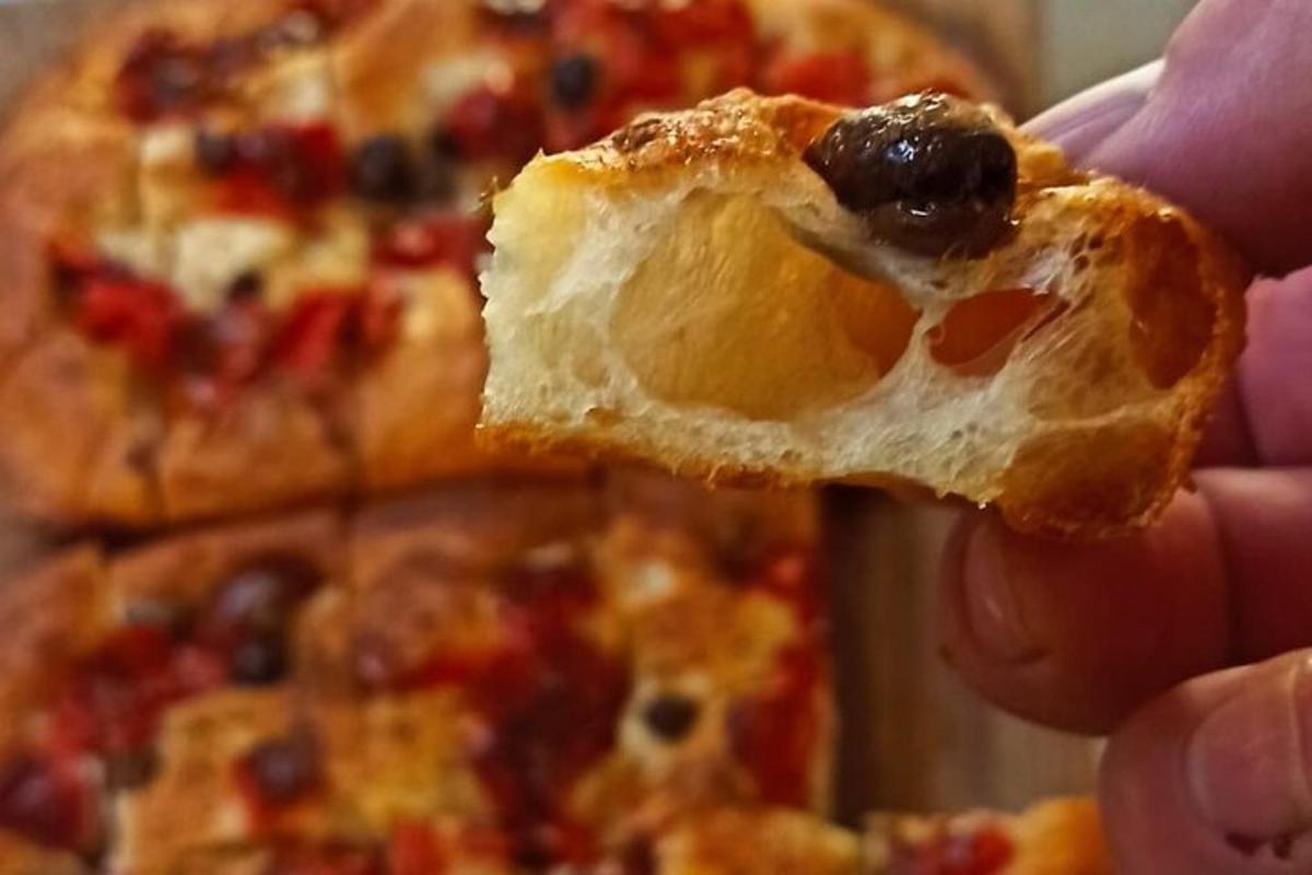 seseorang sedang memegang sekeping piza