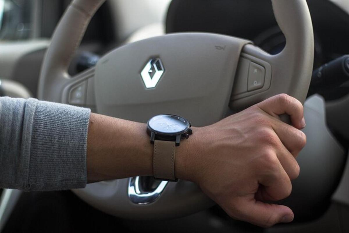 muž řídící auto s hodinkami na paži