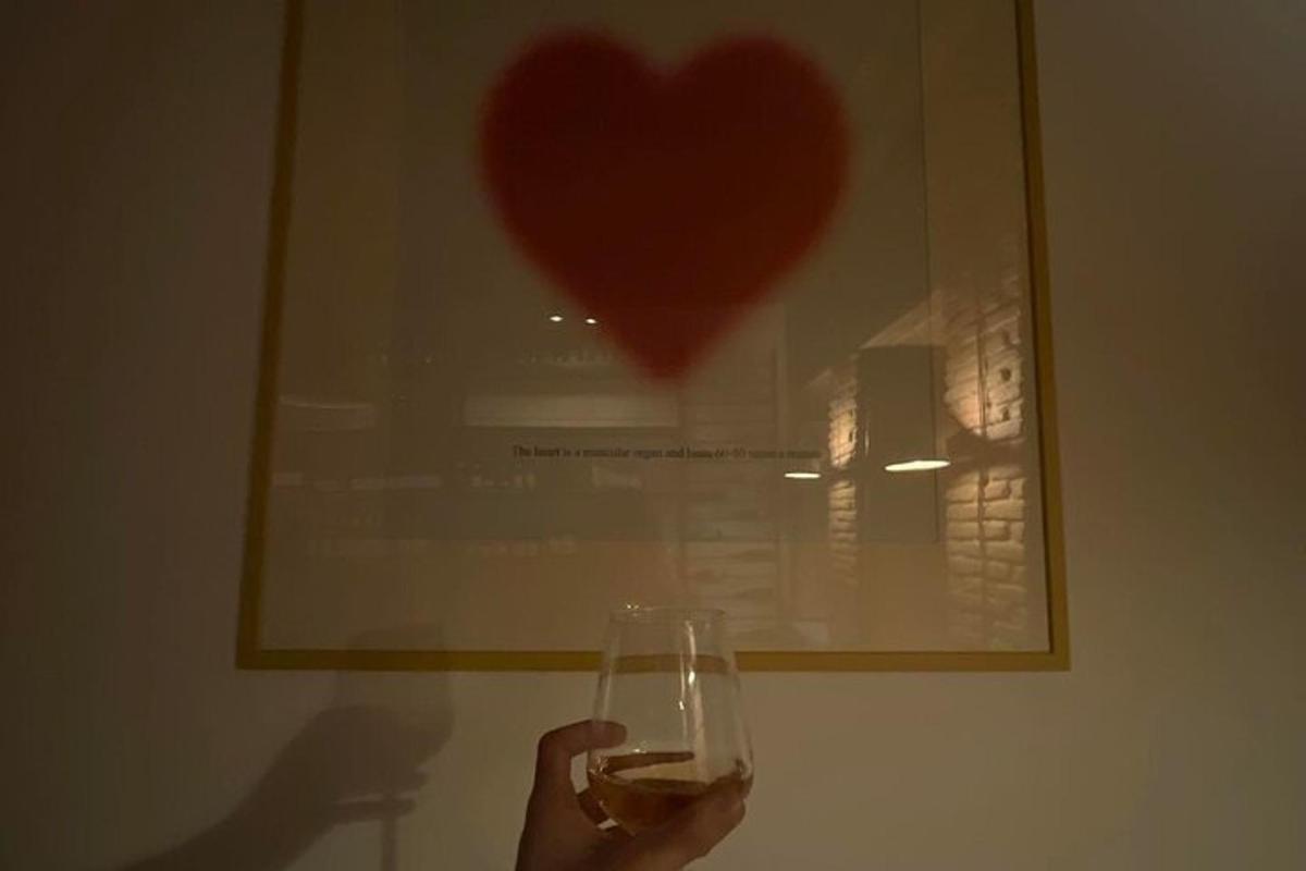 eine Person, die ein Glas Wein vor einem Herzbild hält