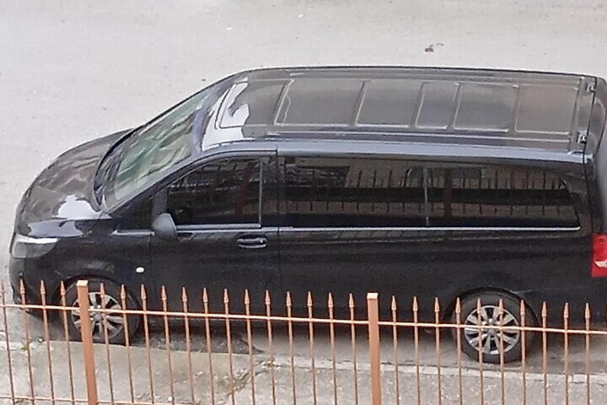 ein schwarzer Lieferwagen, der neben einem Zaun geparkt ist