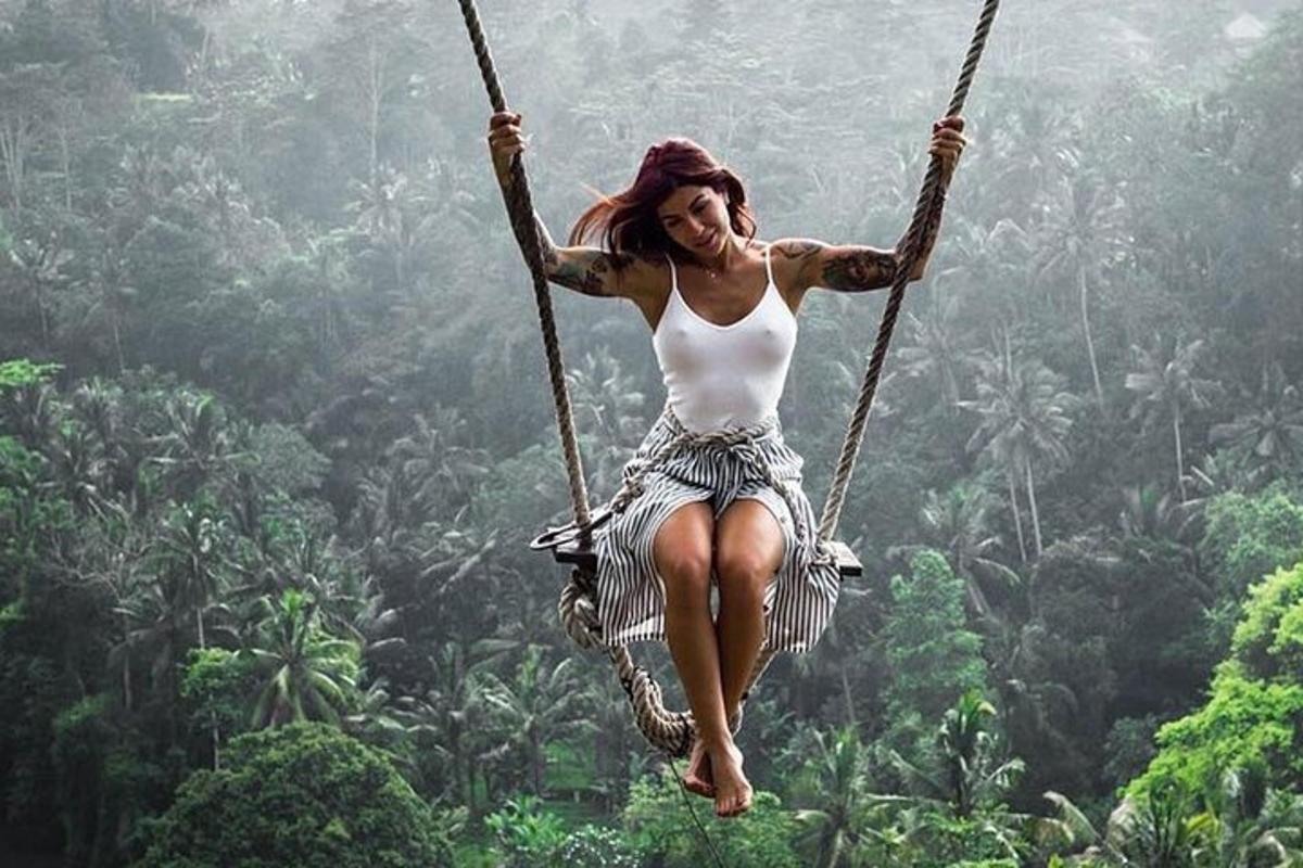 seorang wanita berayun di ayunan tali di hutan