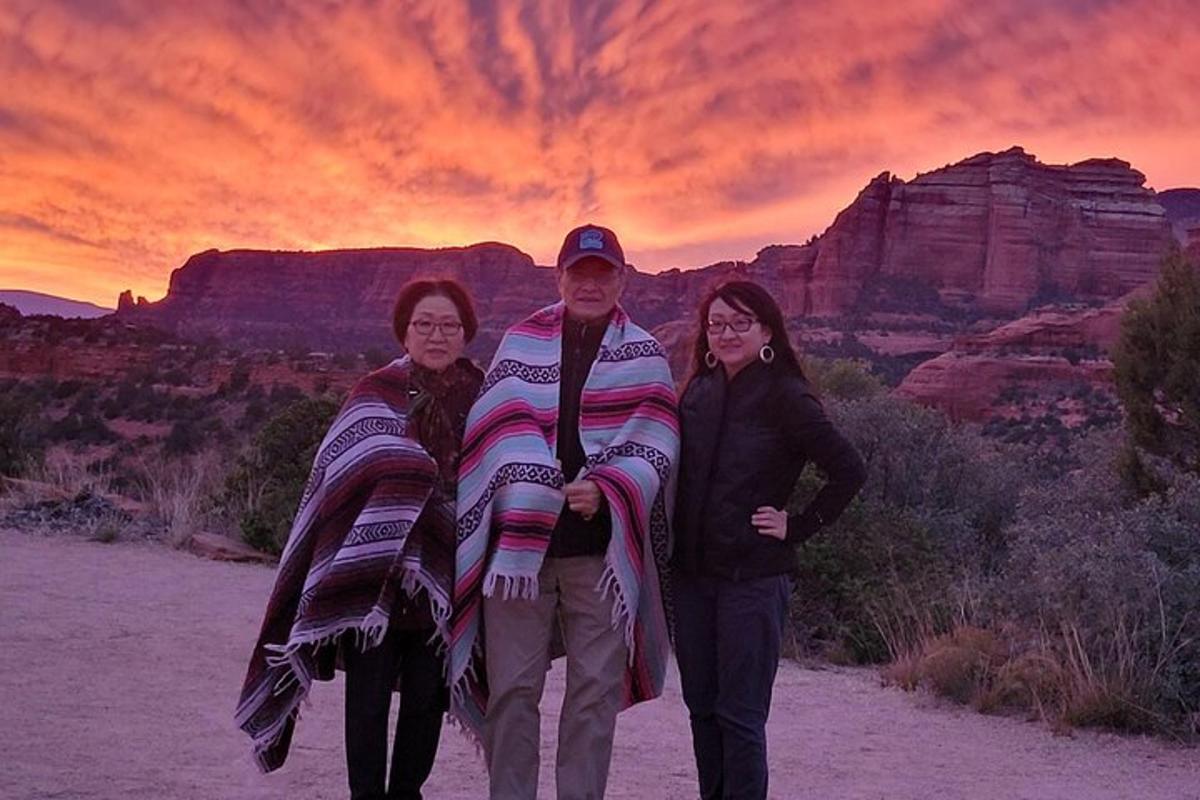Un grupo de tres personas de pie en el desierto al atardecer.