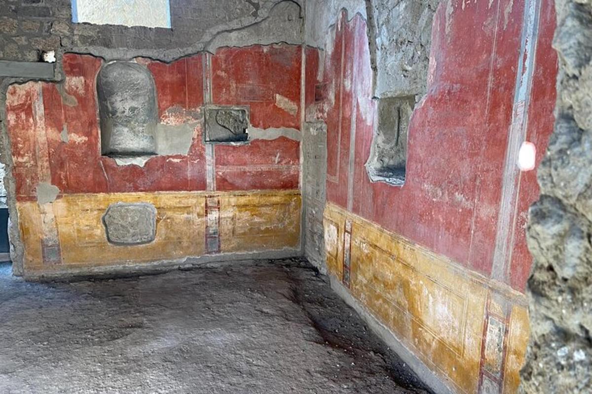 una habitació antiga amb una paret vermella i una porta de fusta