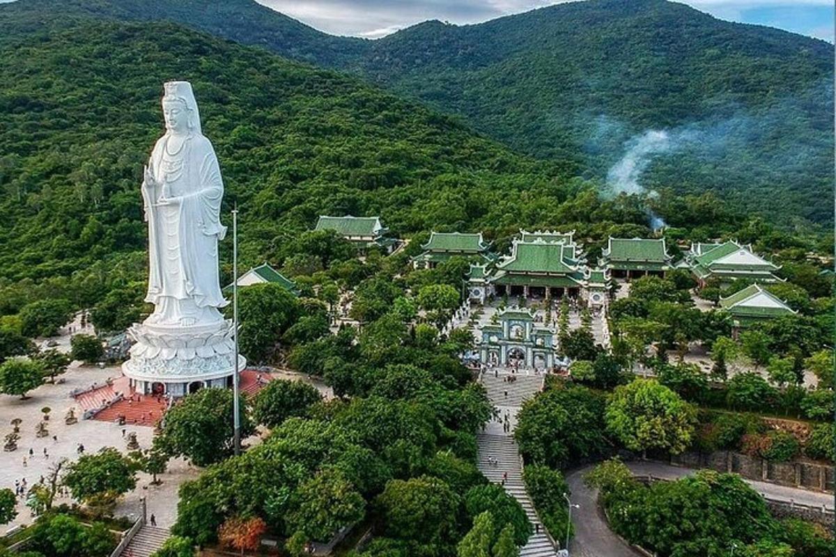 Una gran estatua frente a una ciudad con una montaña.
