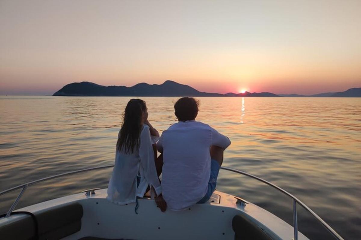 un home i una dona asseguts en un vaixell mirant la posta de sol