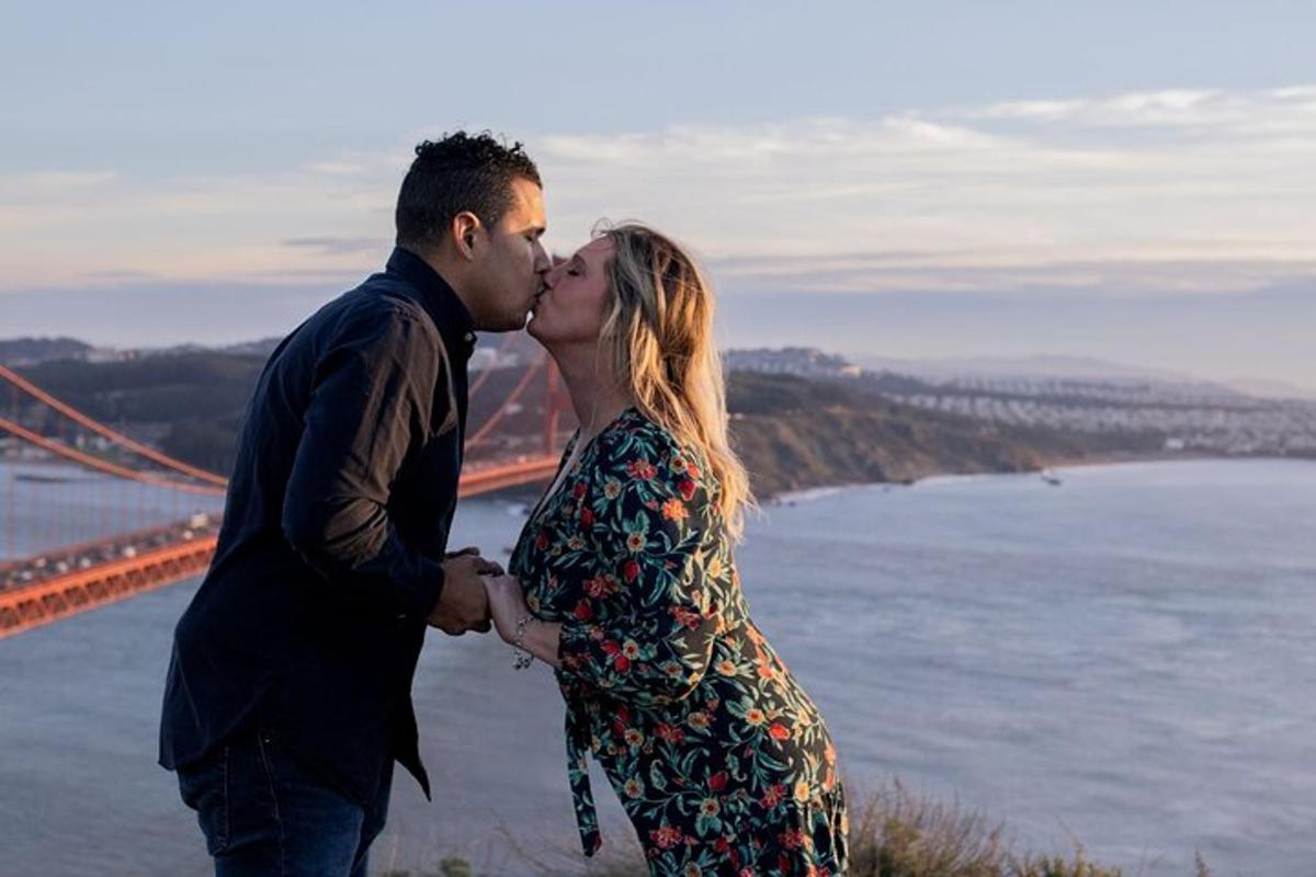Un hombre y una mujer besándose frente a un puente
