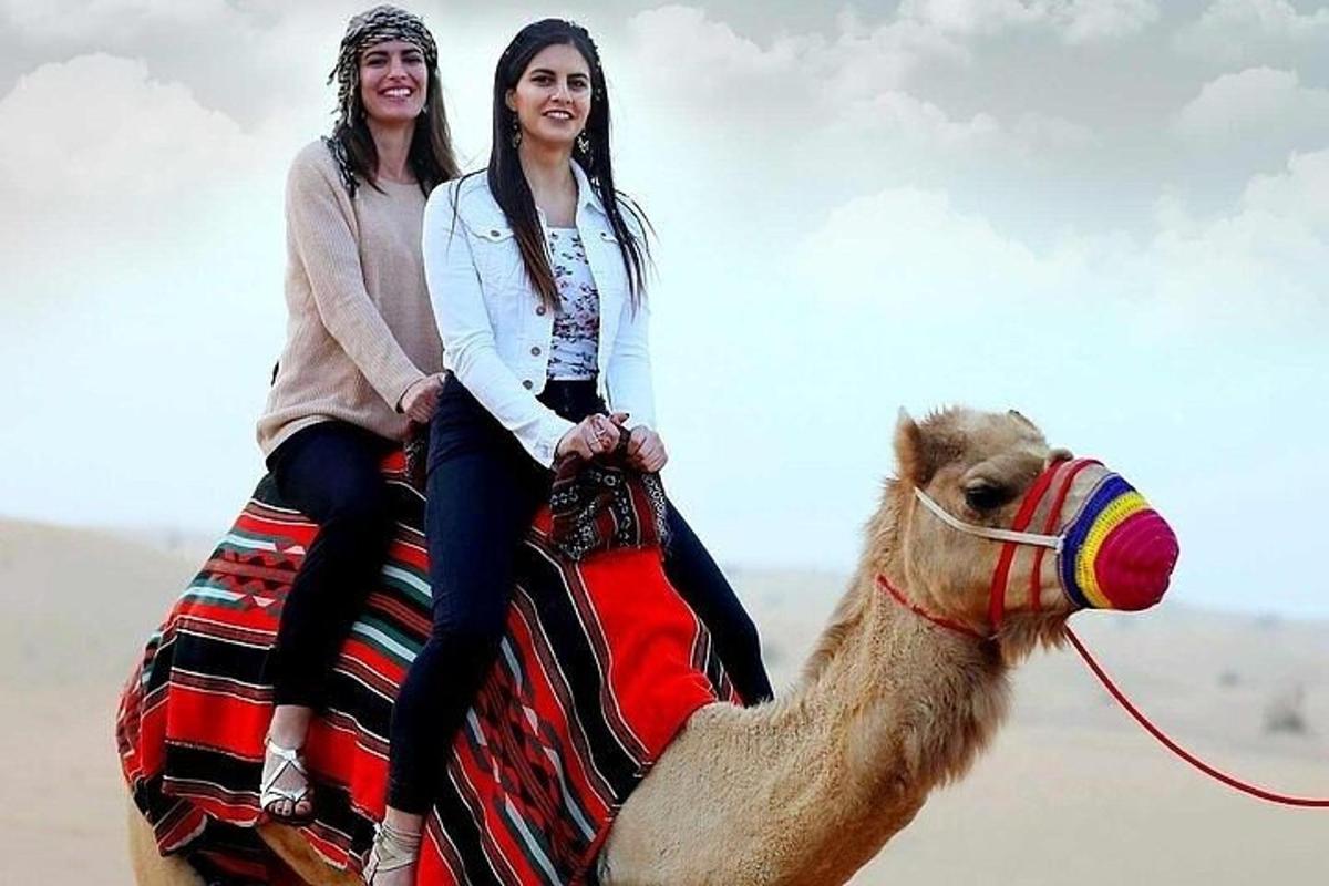 due ragazze a cavallo di un cammello nel deserto