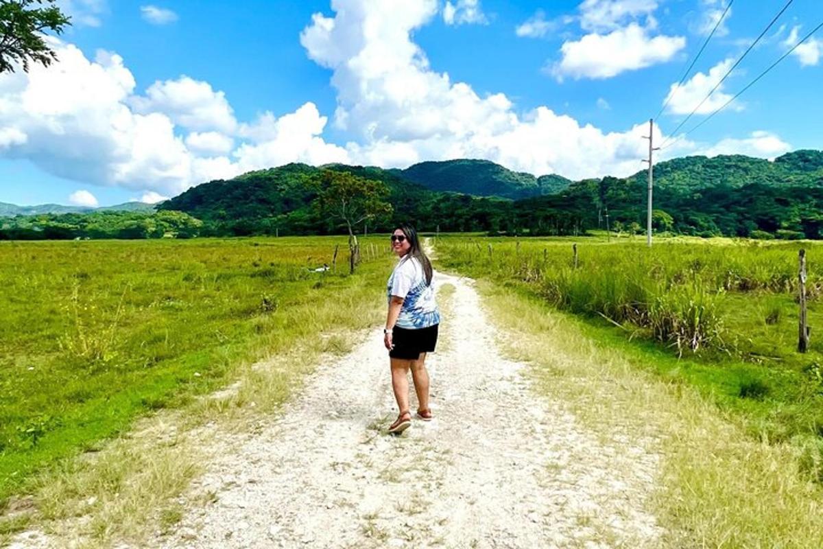una donna in piedi su una strada sterrata in un campo
