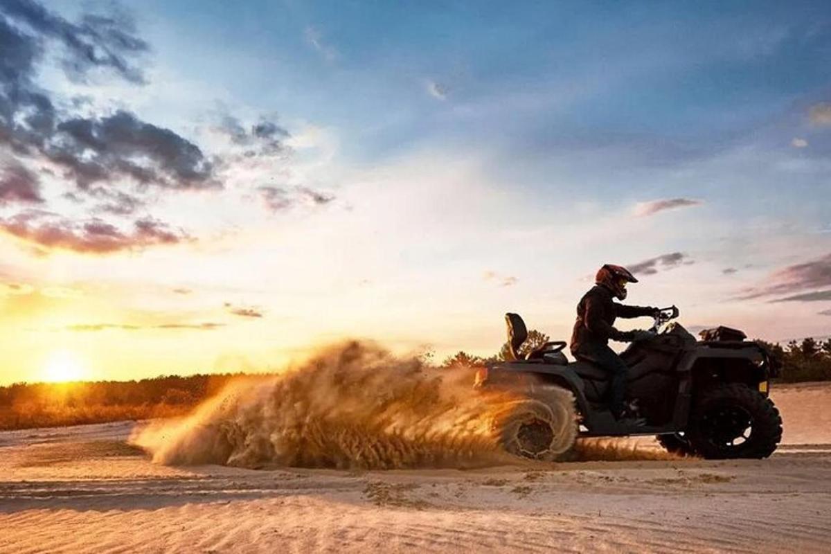 um homem andando de quadriciclo na areia