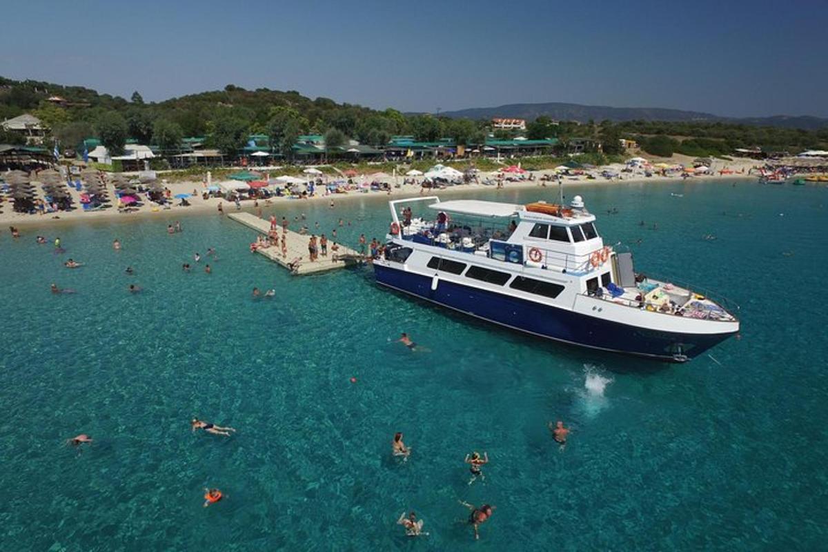 Μια βάρκα είναι αγκυροβολημένη σε μια παραλία με ανθρώπους στο νερό