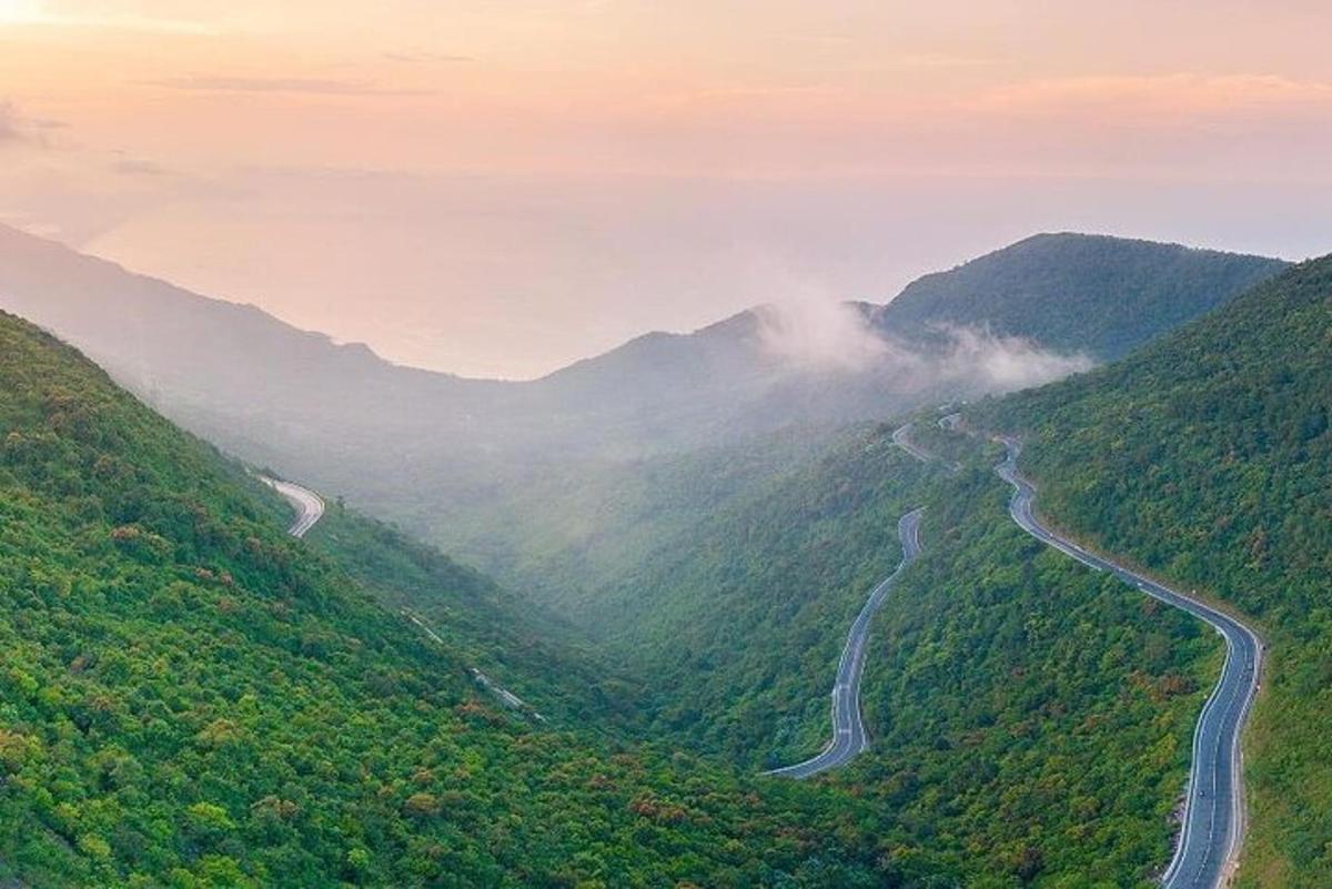 una carretera sinuosa en una vall de muntanya amb boira