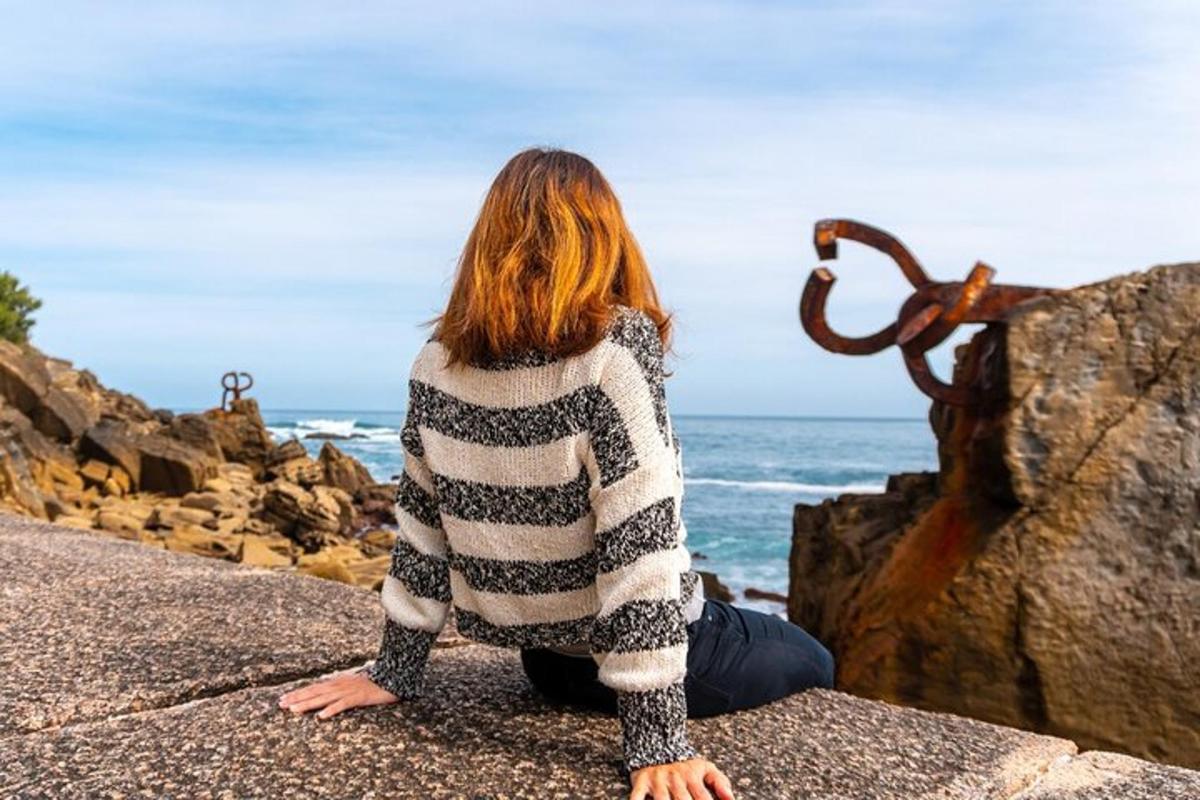 eine Frau, die auf einem Felsen sitzt und auf das Meer blickt