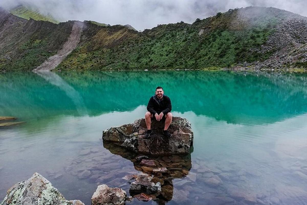 un uomo seduto su una roccia in mezzo a un lago