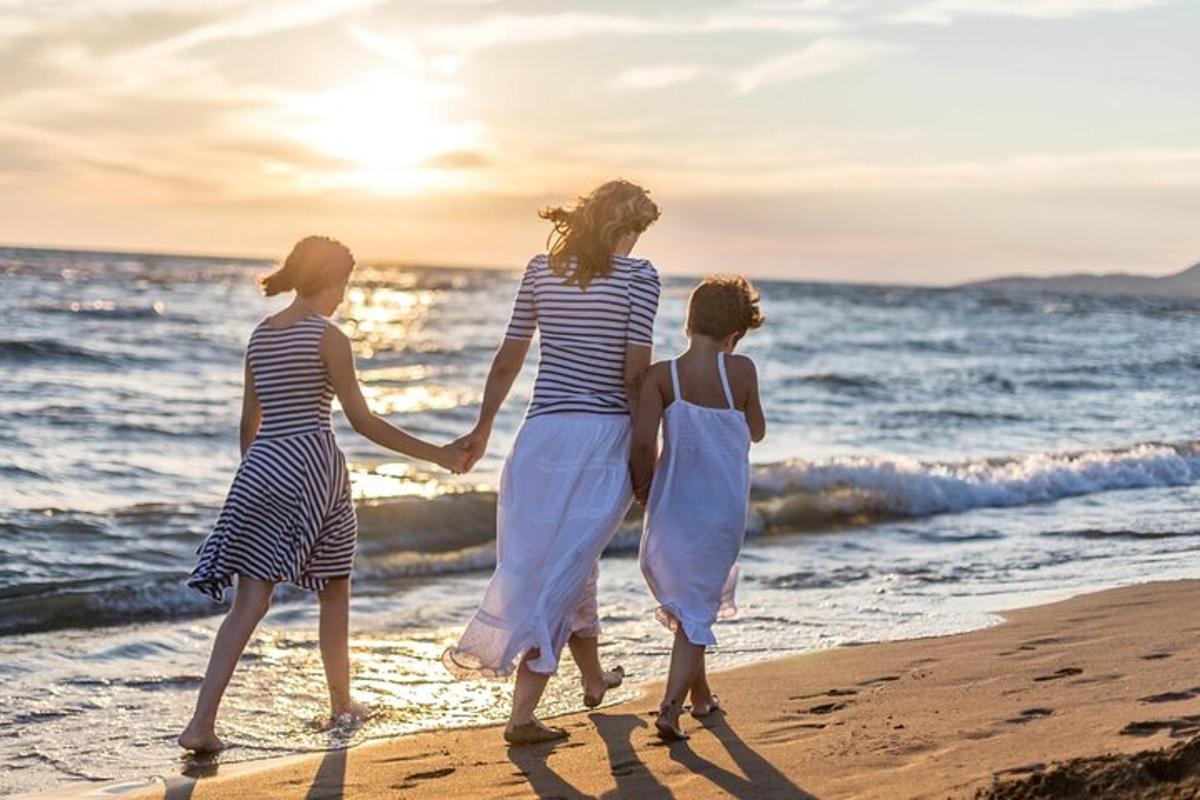 três mulheres caminhando na praia ao pôr do sol