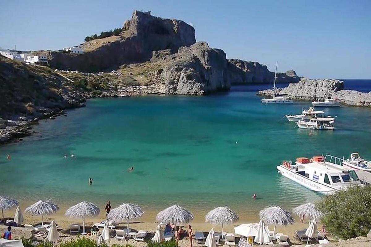 egy strand napernyőkkel és egy csónakkal a vízben