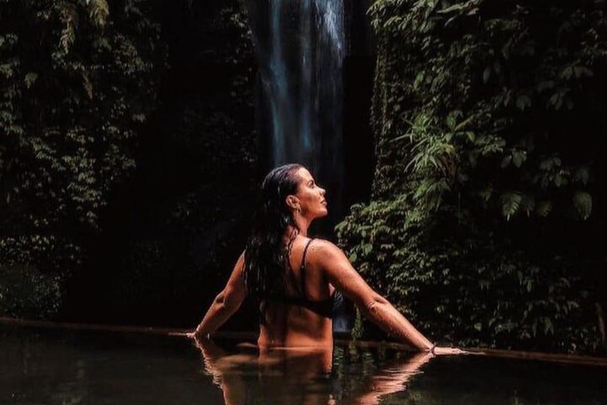 seorang wanita di dalam air di hadapan air terjun
