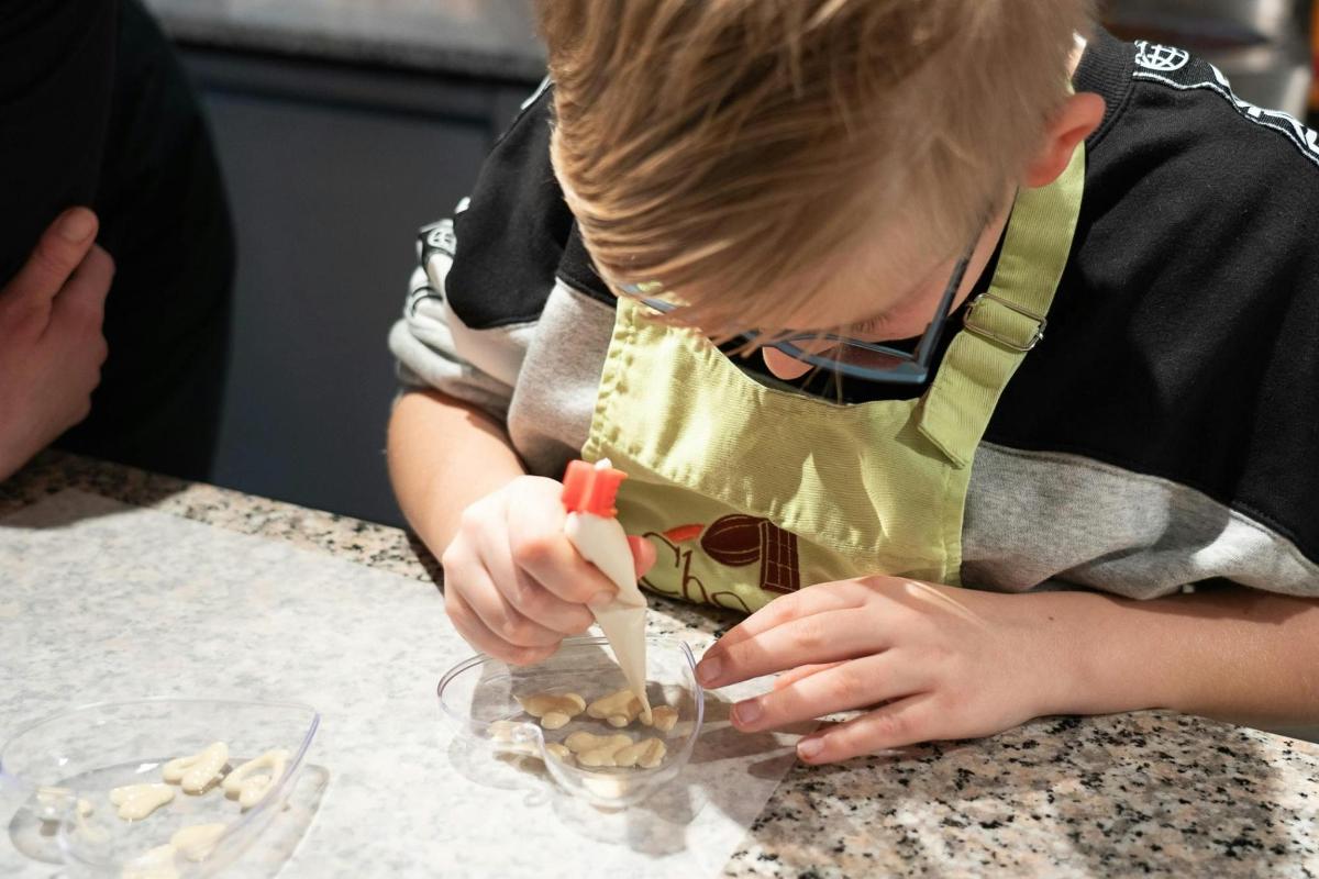 a young boy in a apron putting food into a bowl
