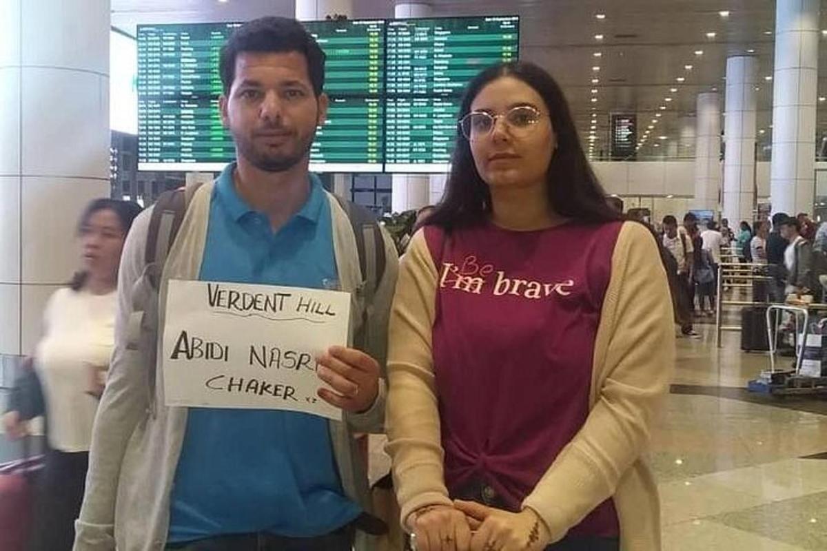 un home i una dona que sostenen un cartell en un aeroport