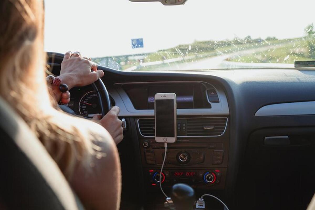 žena řídící auto s mobilním telefonem na volantu