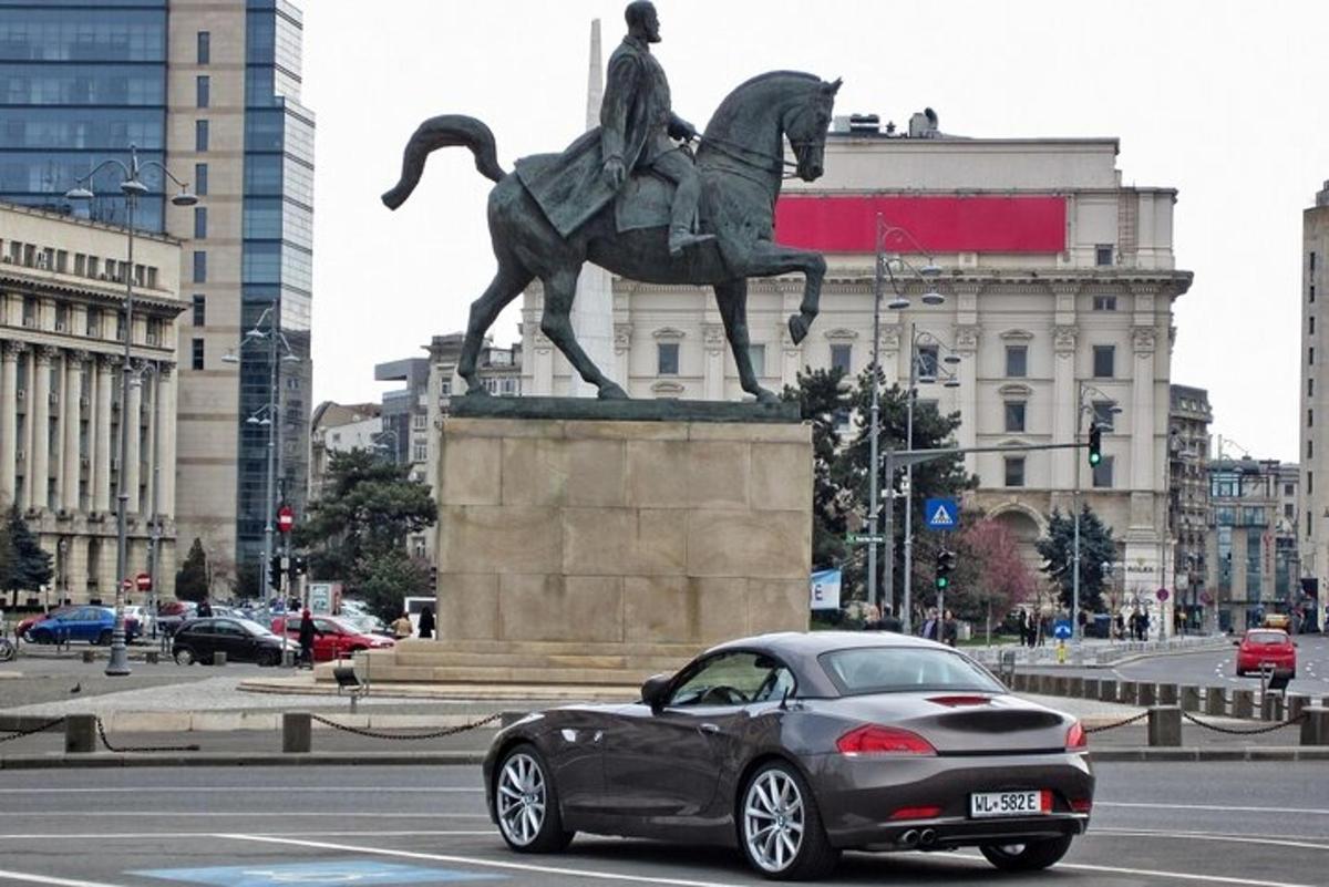 um carro passando por uma estátua de um homem montado num cavalo