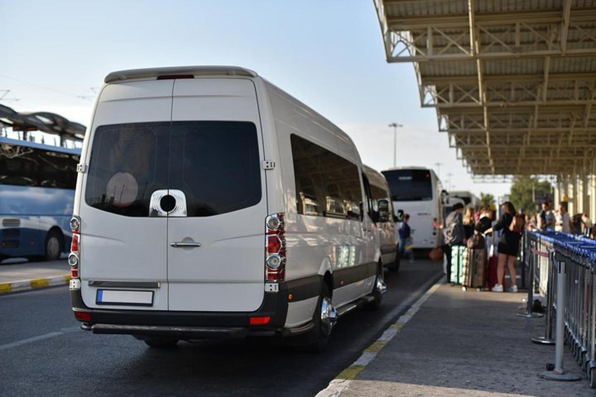 Bílá dodávka parkuje na autobusovém nádraží