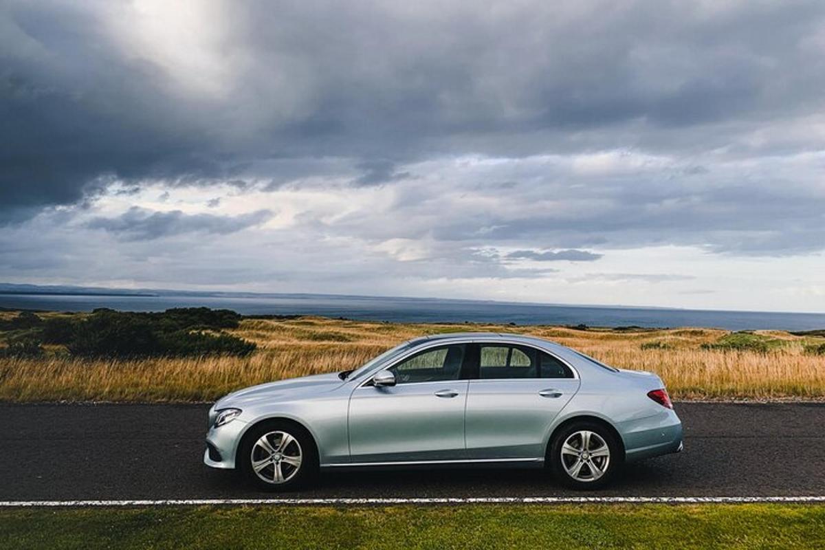 a silver car parked on a road near the ocean