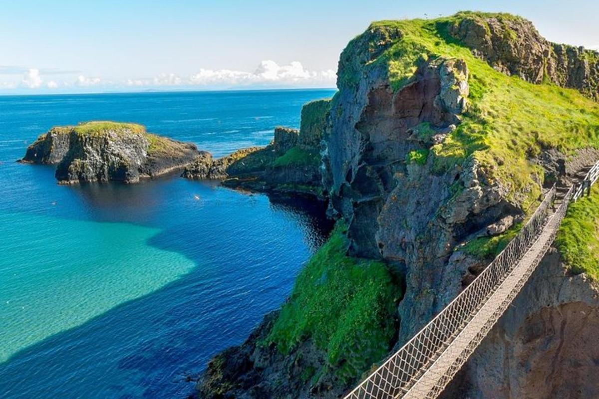 a suspension bridge over the ocean next to a cliff