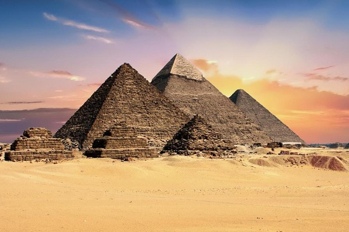 en gruppe pyramider i ørkenen ved solnedgang