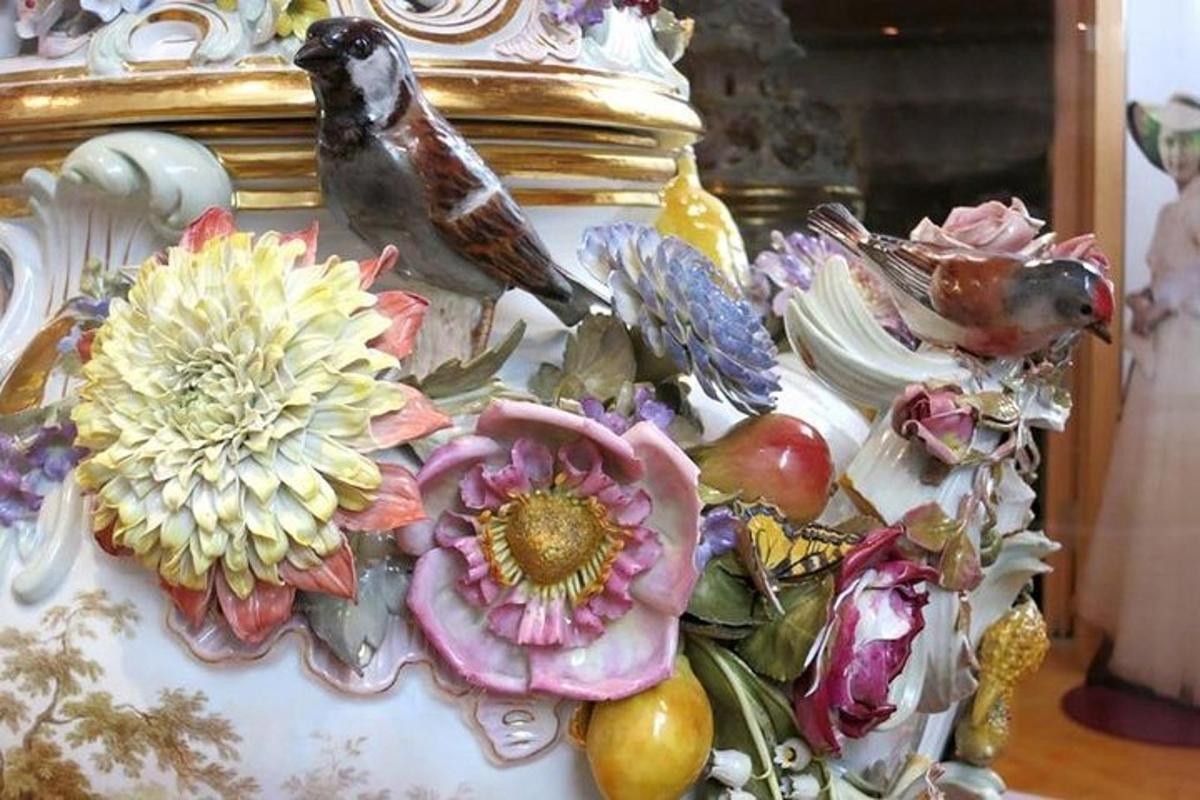 o pasăre așezată pe o vază cu flori pe ea