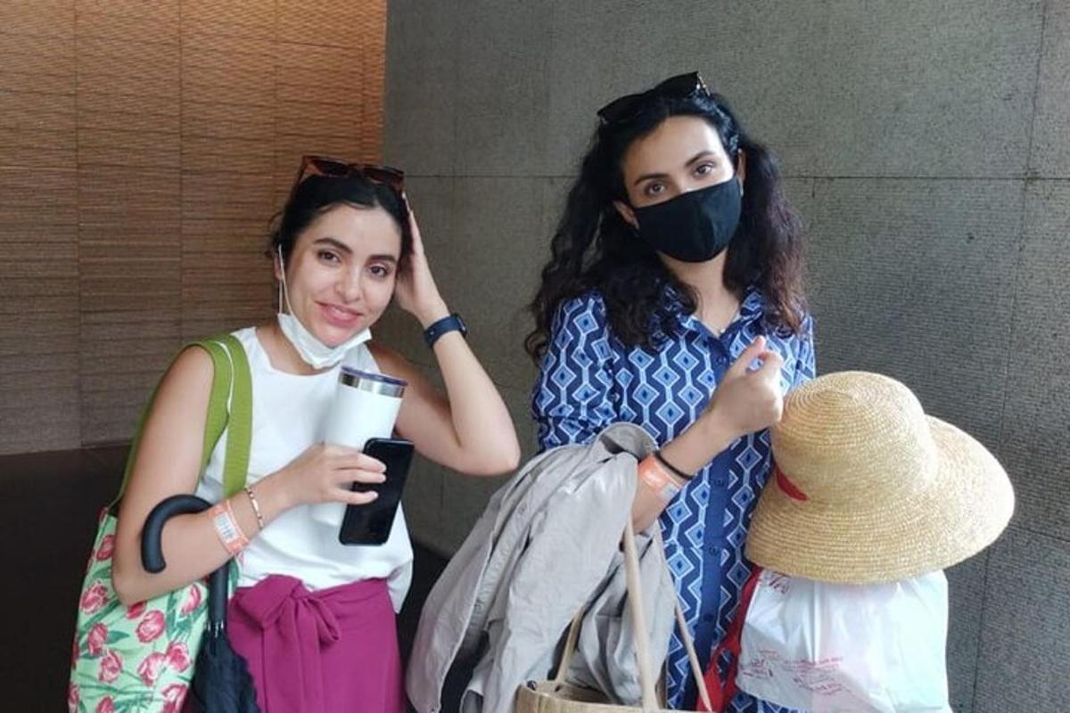 two women standing next to each other wearing masks