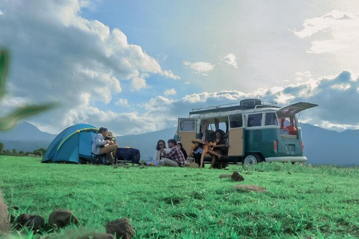 Un grupo de personas sentadas en un campo junto a una camioneta.