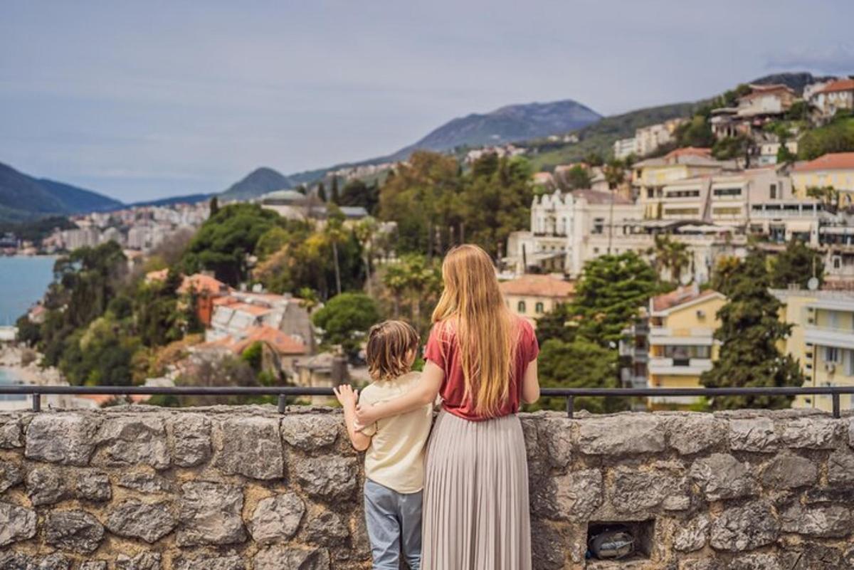 uma mulher e uma criança em pé em um muro olhando para uma cidade