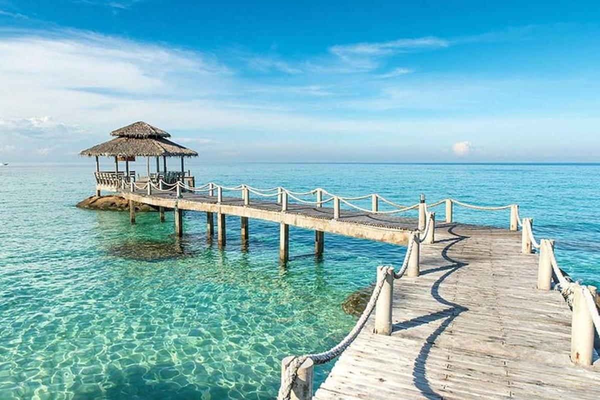 a wooden pier in the water with a thatch roof