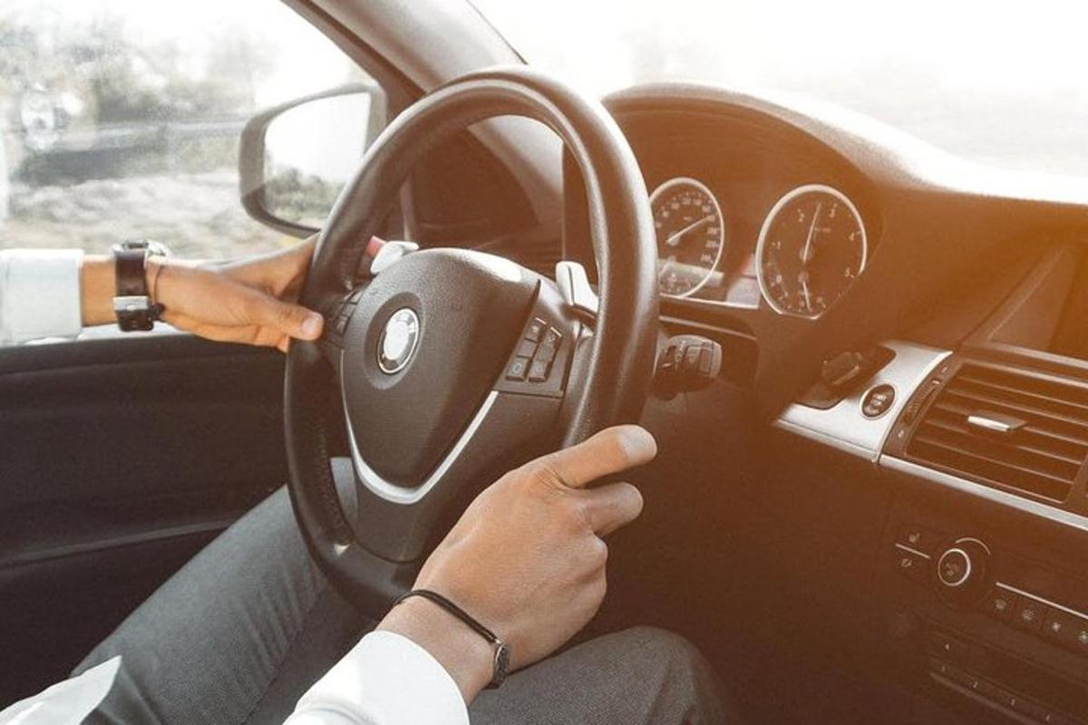 osoba řídící auto s rukou na volantu