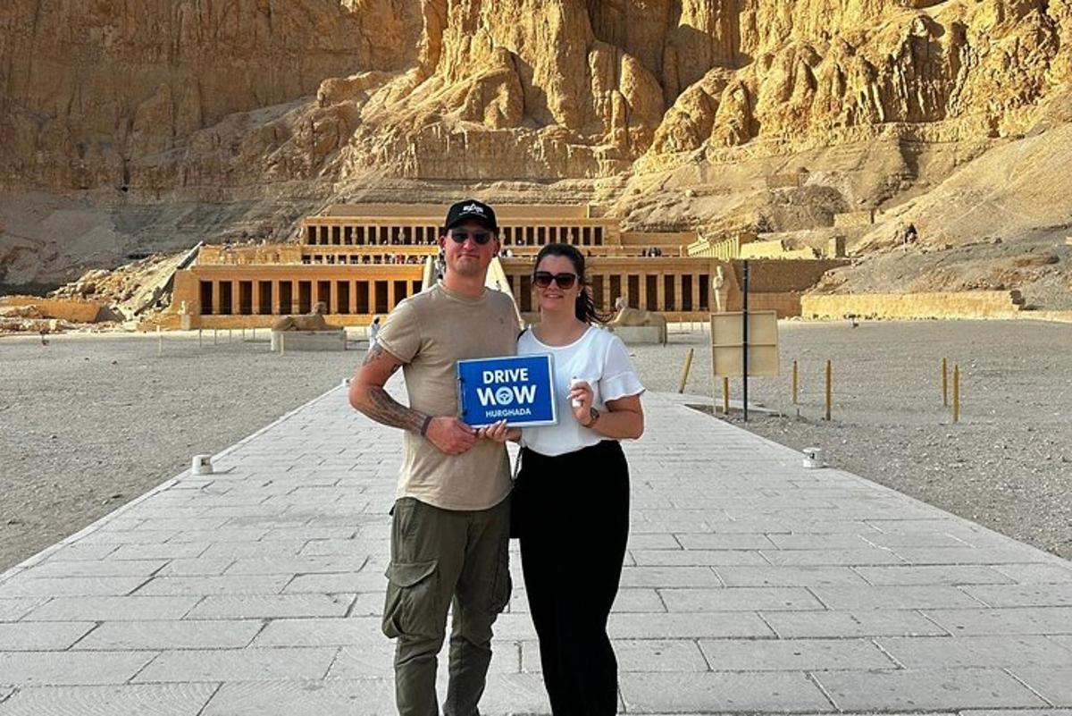 a man and woman holding a sign in front of a building