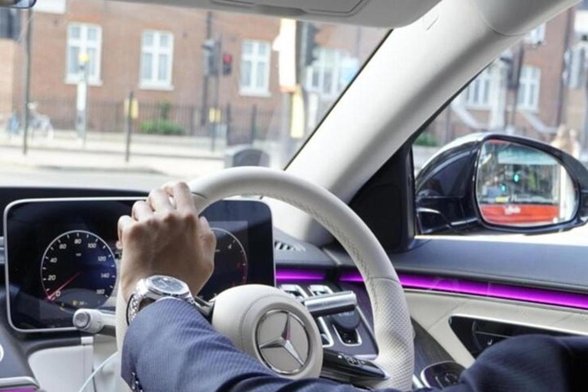 muž řídící auto s rukama na volantu